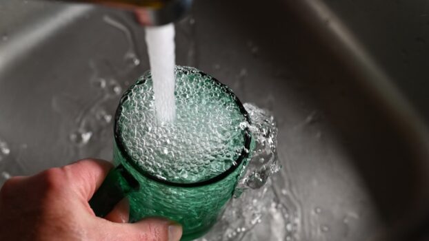 A close-up of a water filtration system with clear water flowing, highlighting the importance of proper installation and maintenance.