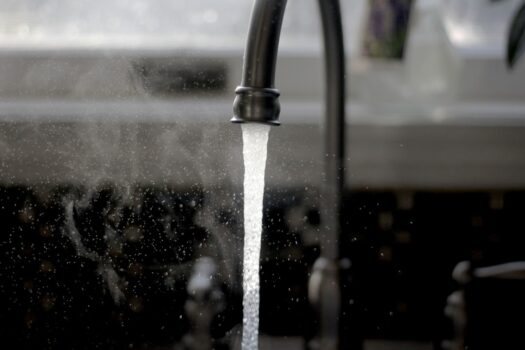 A family enjoying clean water at home, showcasing a water filter or a glass of fresh water in a bright kitchen setting.